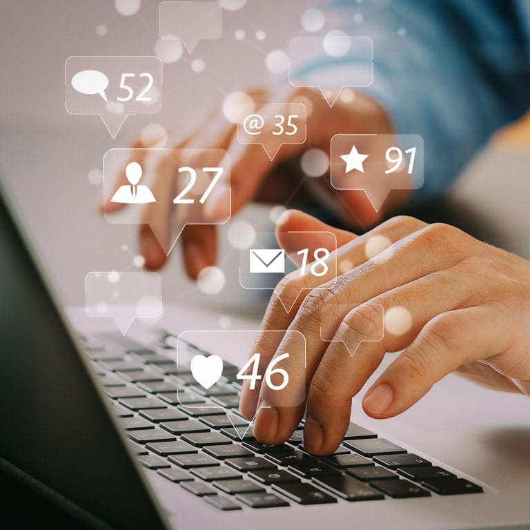 Close up of a man's hands using laptop on desk with creative social media community, likes, and shares icons as a hologram